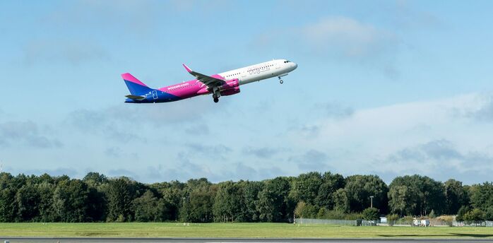 Wizz Air aircraft taking off above an airport runway