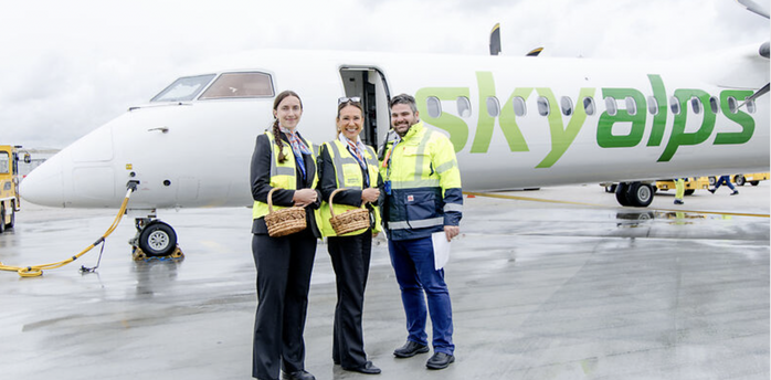 SkyAlps staff standing beside an aircraft at Salzburg Airport