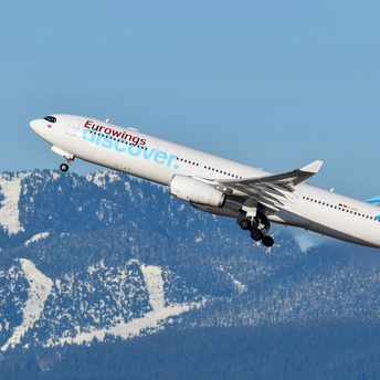 Eurowings aircraft departing over snowy mountains