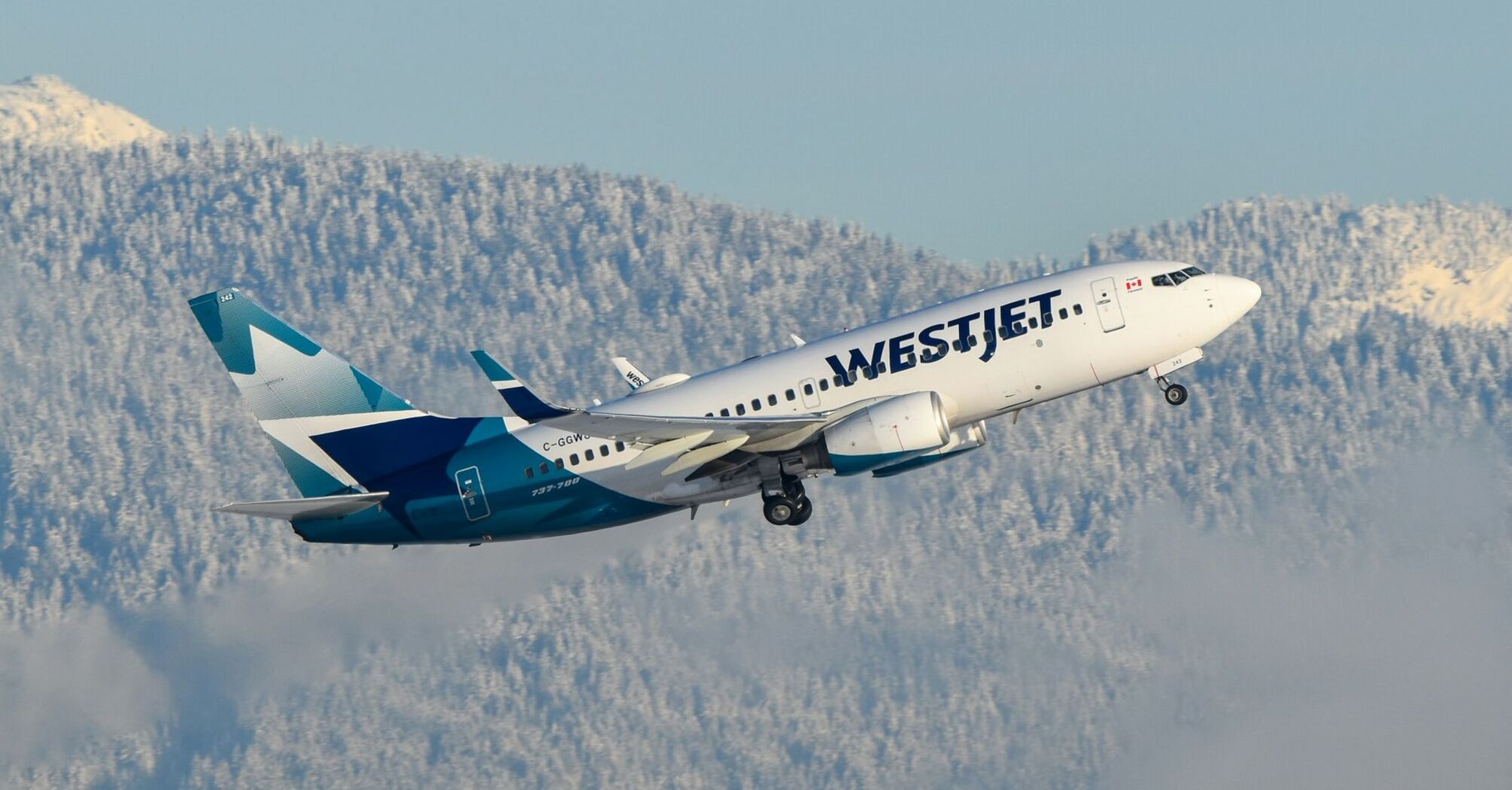 WestJet aircraft flying over snowy mountains