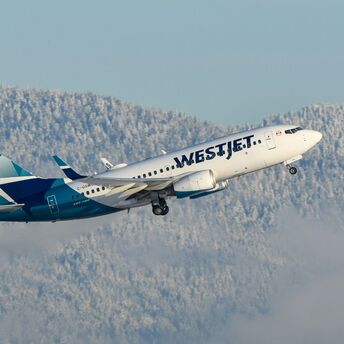 WestJet aircraft flying over snowy mountains