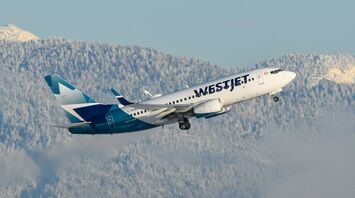 WestJet aircraft flying over snowy mountains