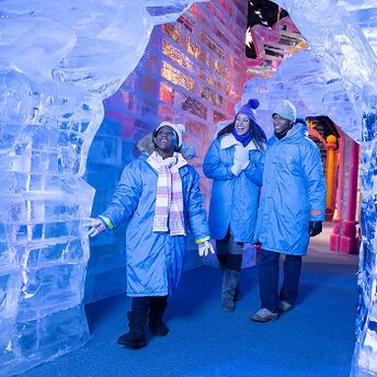 Visitors exploring hand-carved ice sculptures at Gaylord Rockies