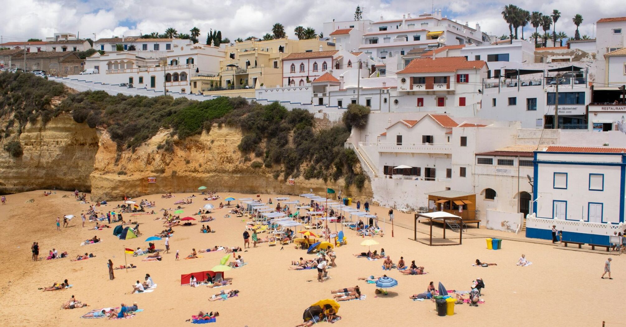 Busy Portuguese beach below whitewashed coastal buildings