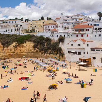 Busy Portuguese beach below whitewashed coastal buildings