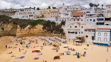 Busy Portuguese beach below whitewashed coastal buildings