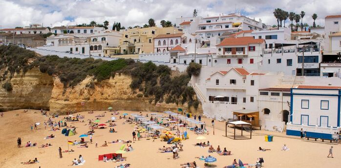 Busy Portuguese beach below whitewashed coastal buildings