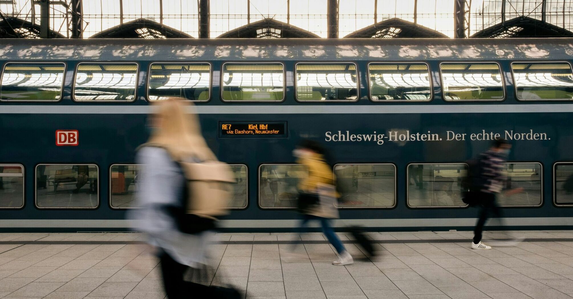 Deutsche Bahn passengers pass a double-decker train at a German station