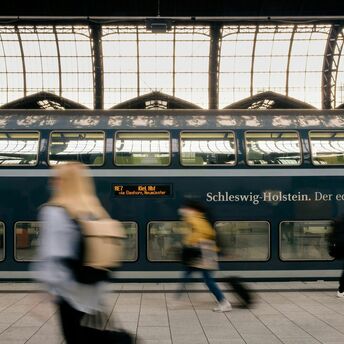 Deutsche Bahn passengers pass a double-decker train at a German station