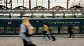 Deutsche Bahn passengers pass a double-decker train at a German station