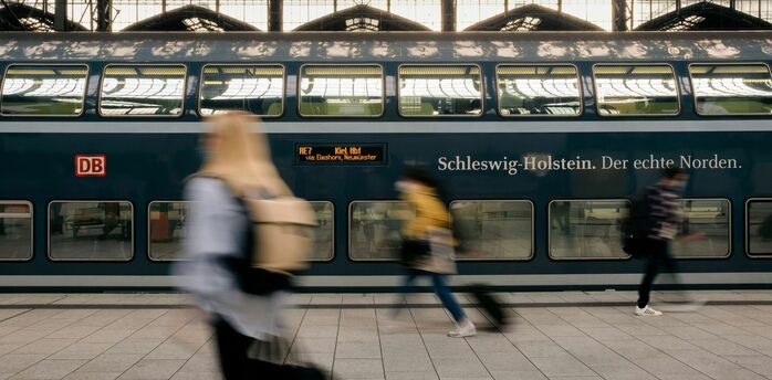 Deutsche Bahn passengers pass a double-decker train at a German station