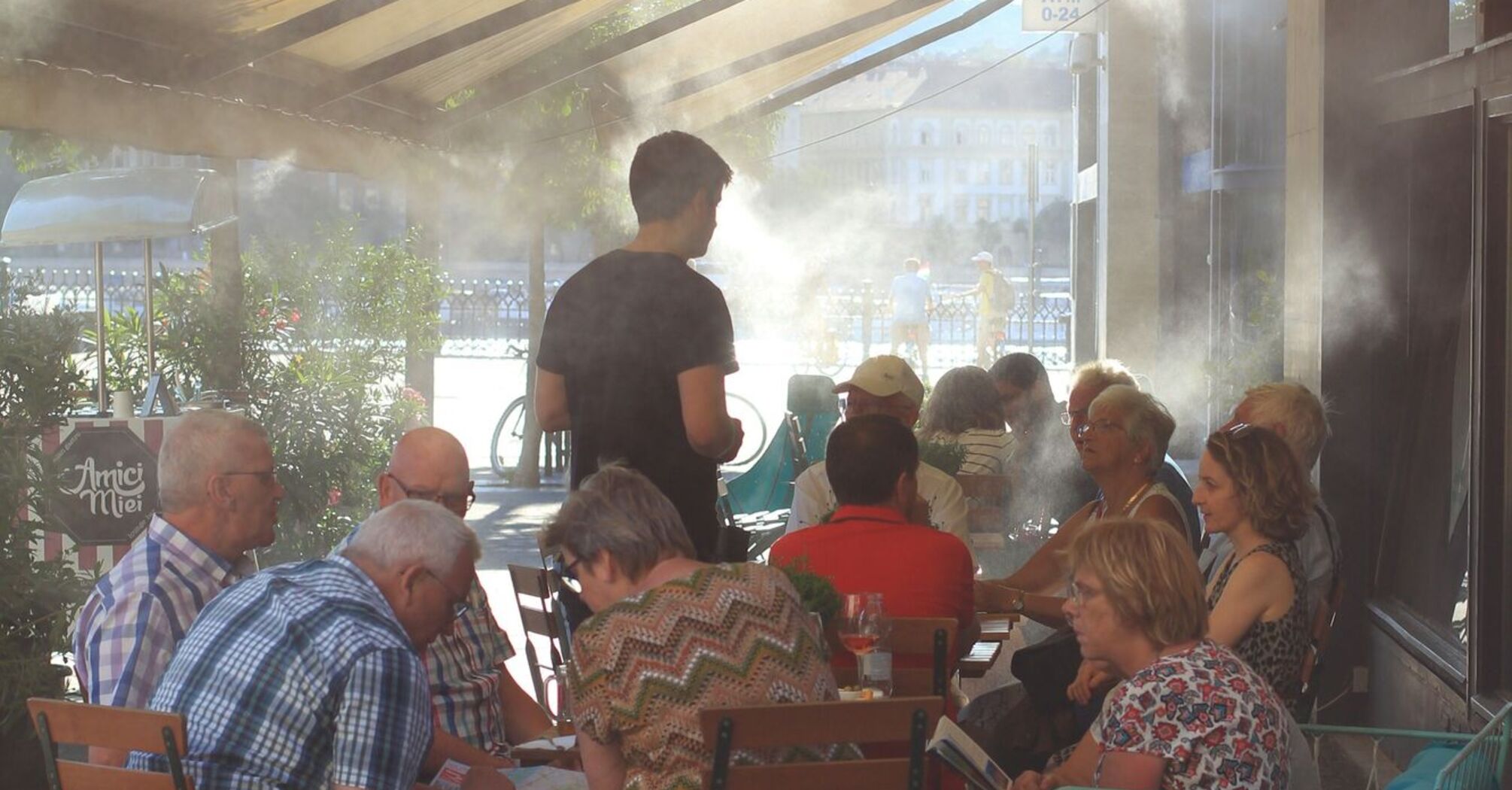 People sitting beneath mist cooling system