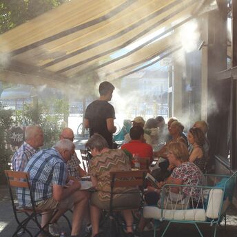 People sitting beneath mist cooling system