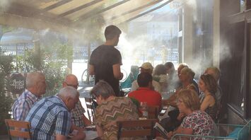 People sitting beneath mist cooling system