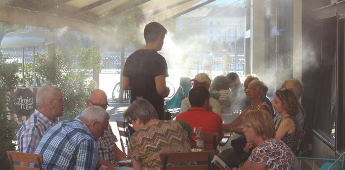 People sitting beneath mist cooling system