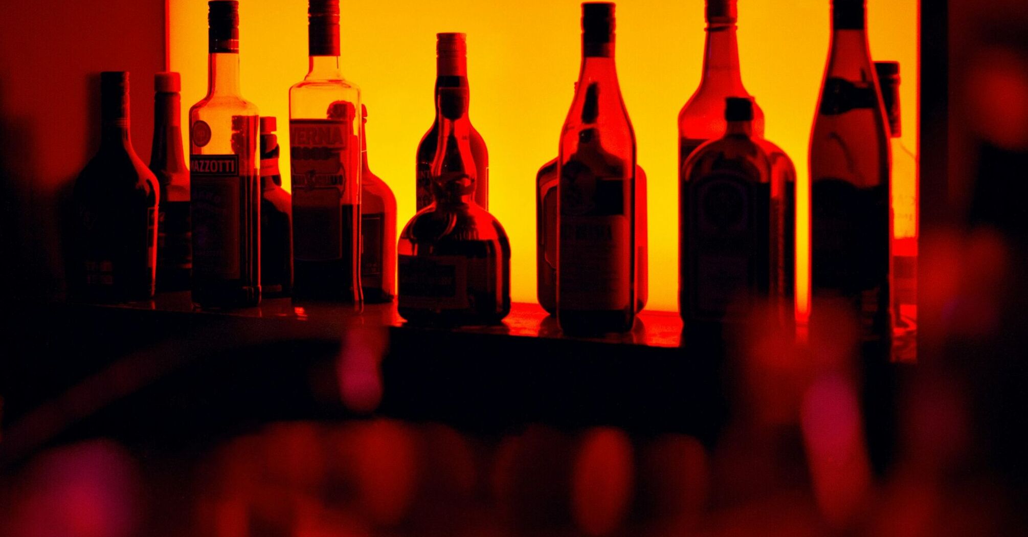 Backlit bottles behind a cocktail bar