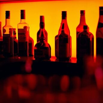 Backlit bottles behind a cocktail bar