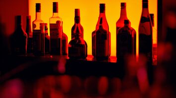 Backlit bottles behind a cocktail bar