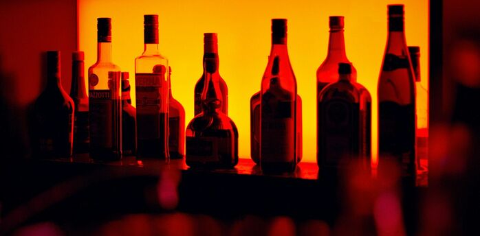Backlit bottles behind a cocktail bar