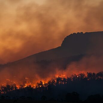 Wildfire burning across hills at sunset