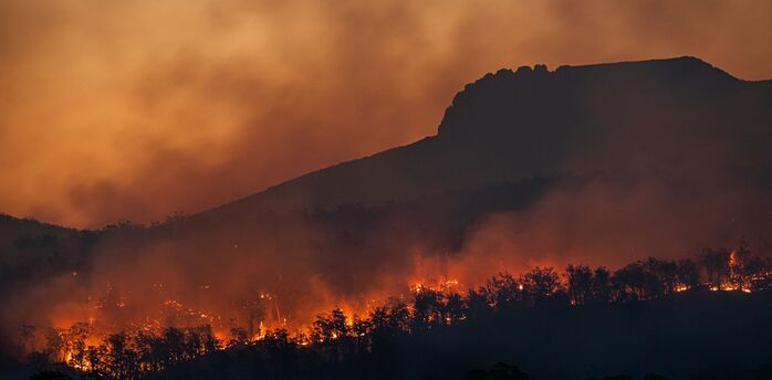 Wildfire burning across hills at sunset