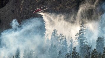 Firefighting helicopter dropping water over a forest