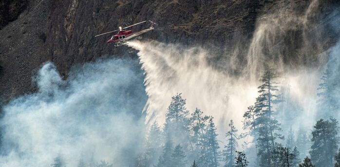 Firefighting helicopter dropping water over a forest