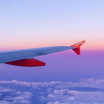 easyJet aircraft wing above clouds at sunset