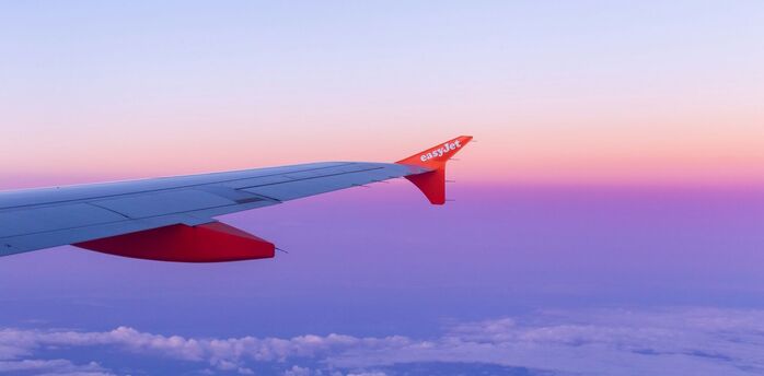 easyJet aircraft wing above clouds at sunset
