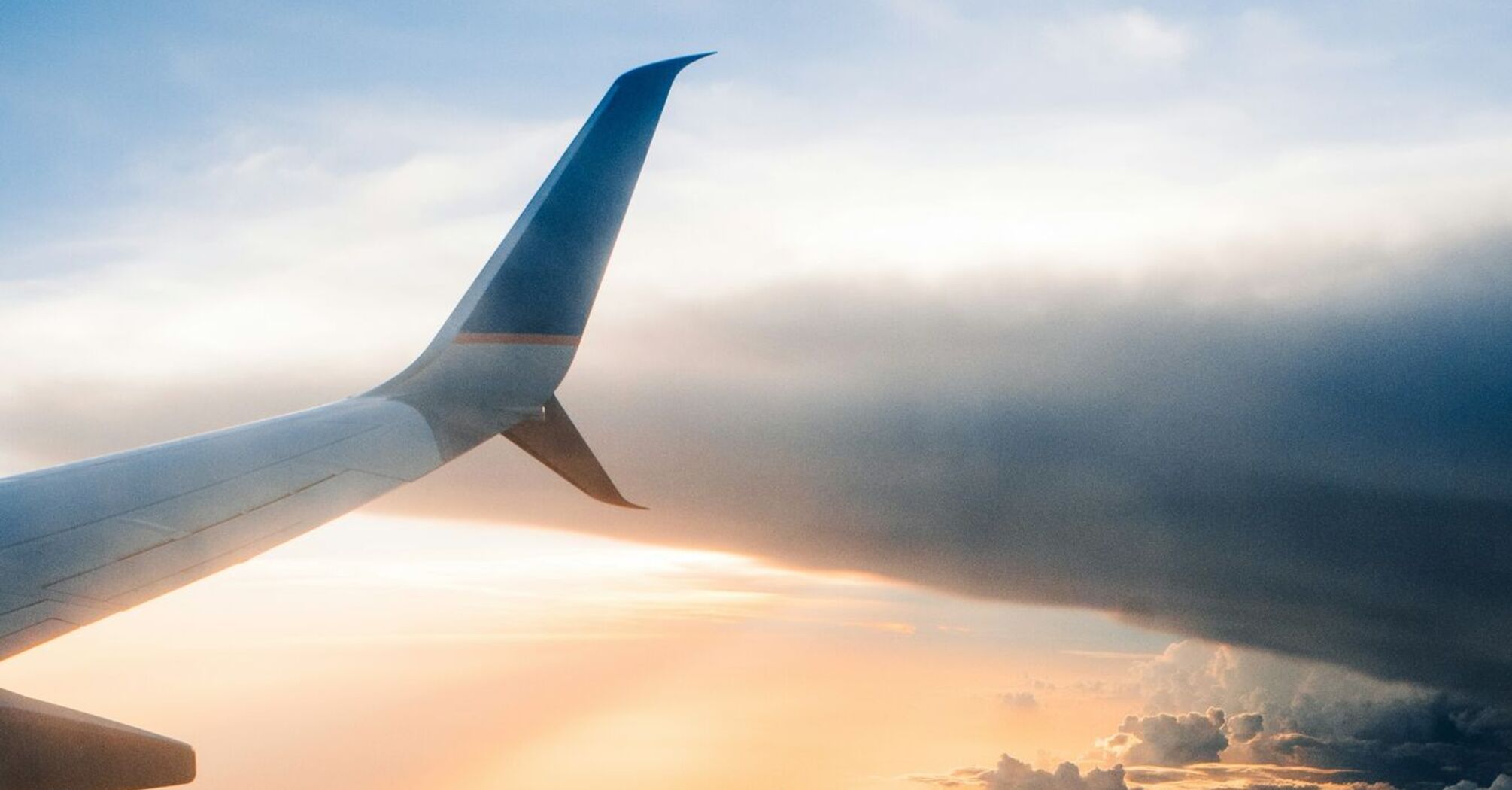 Airplane wing above clouds at sunset 
