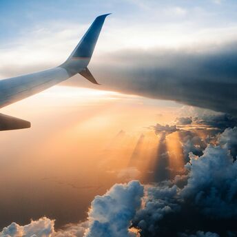 Airplane wing above clouds at sunset