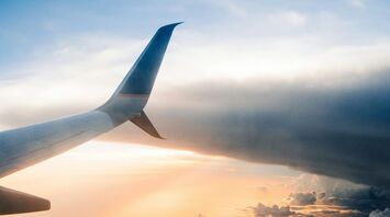 Airplane wing above clouds at sunset