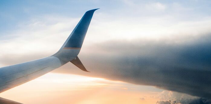 Airplane wing above clouds at sunset
