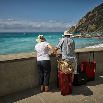 Older couple travelling with luggage by the sea