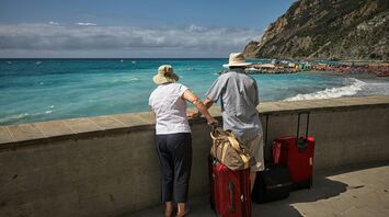 Older couple travelling with luggage by the sea
