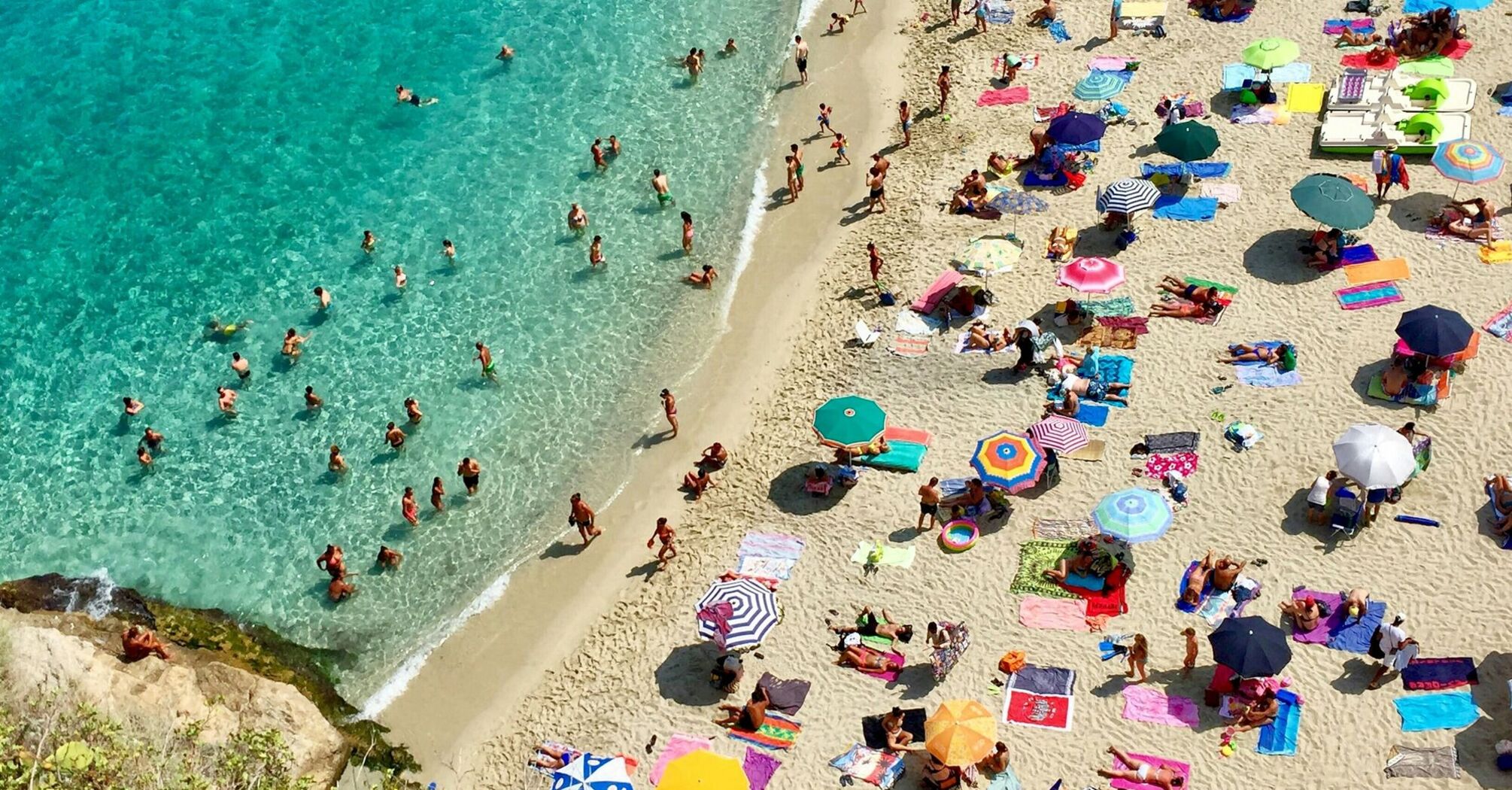 Crowded Italian beach with parasols and swimmers