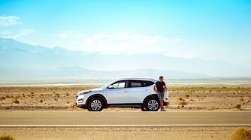 Driver standing beside a rental car on a road