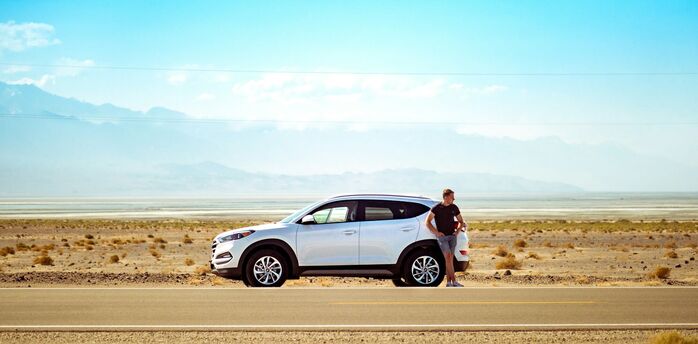 Driver standing beside a rental car on a road