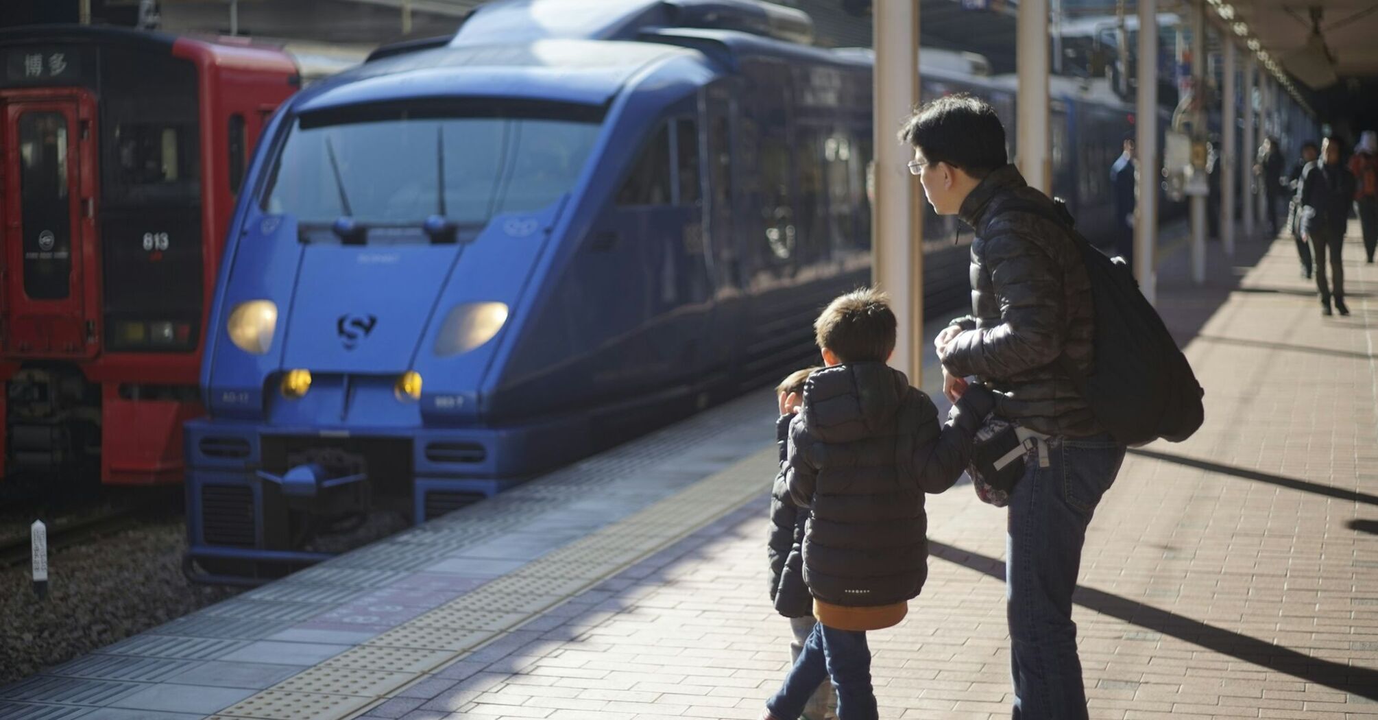 Parent and child waiting beside trains at a station
