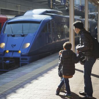 Parent and child waiting beside trains at a station