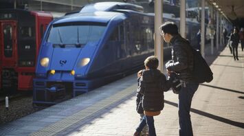 Parent and child waiting beside trains at a station