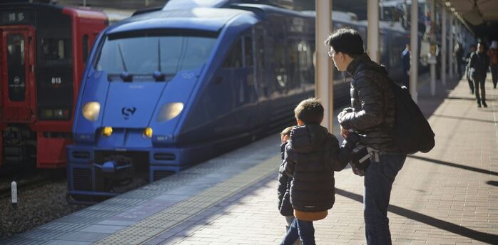 Parent and child waiting beside trains at a station