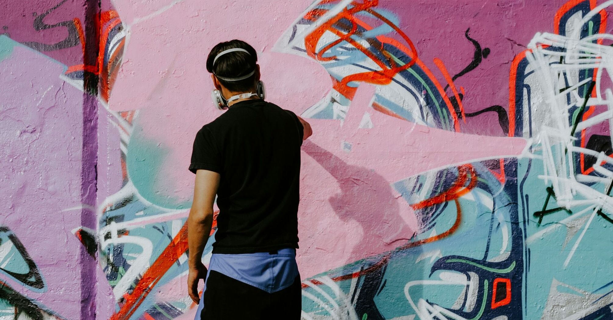 Street artist painting a colourful graffiti wall