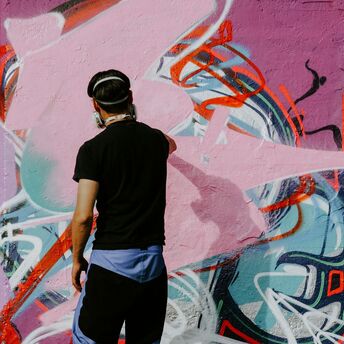 Street artist painting a colourful graffiti wall