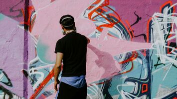 Street artist painting a colourful graffiti wall
