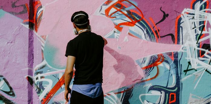 Street artist painting a colourful graffiti wall