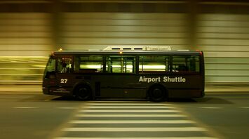 Airport shuttle bus travelling beside a terminal