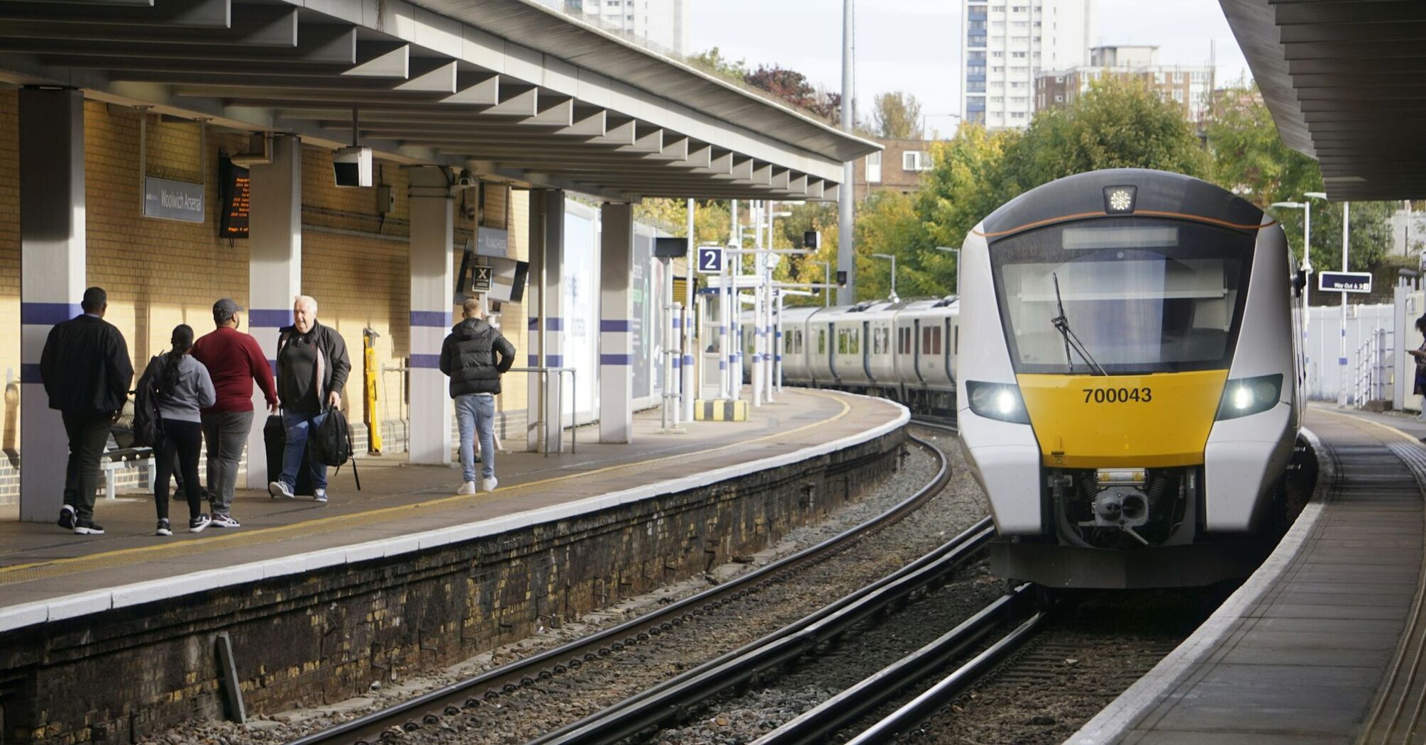 Passengers beside a commuter train at a UK station
