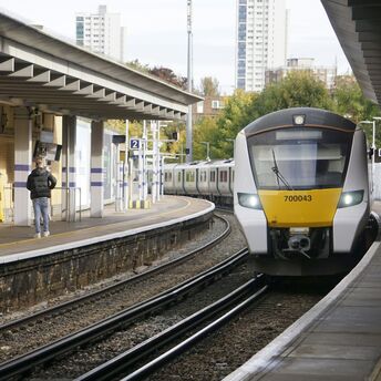 Passengers beside a commuter train at a UK station