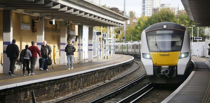 Passengers beside a commuter train at a UK station